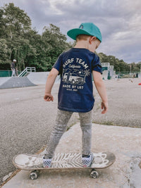 Child skateboarding in blue Surf Team tee and jeans.
